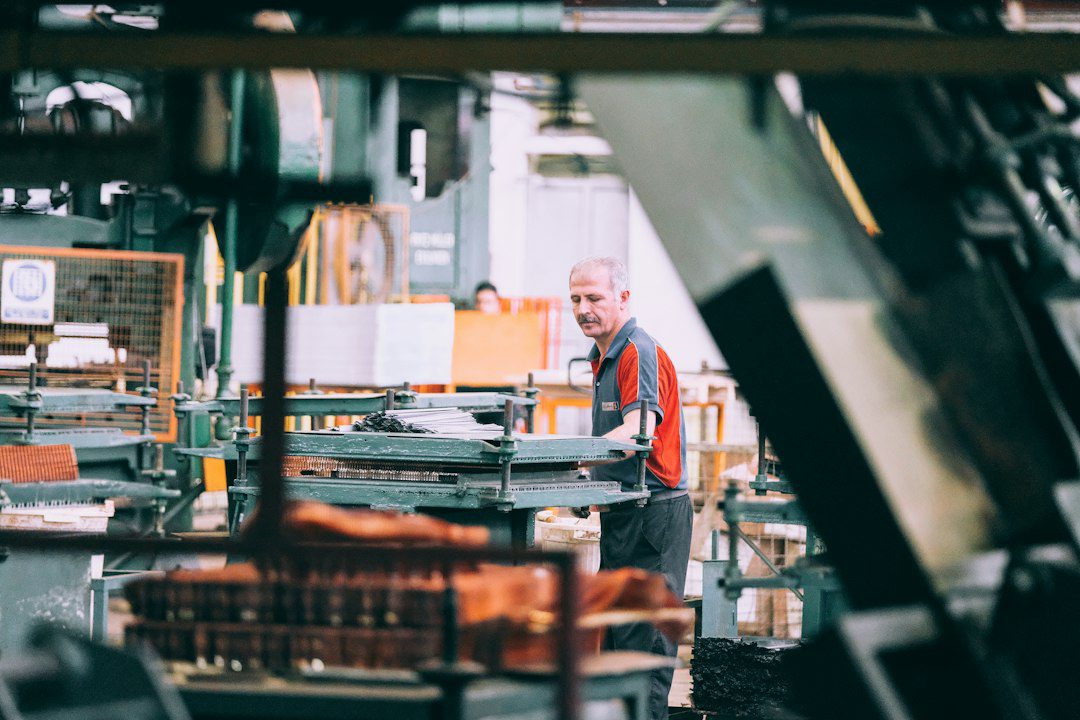 Factory worker operating industrial machinery — reducing defect waste in manufacturing